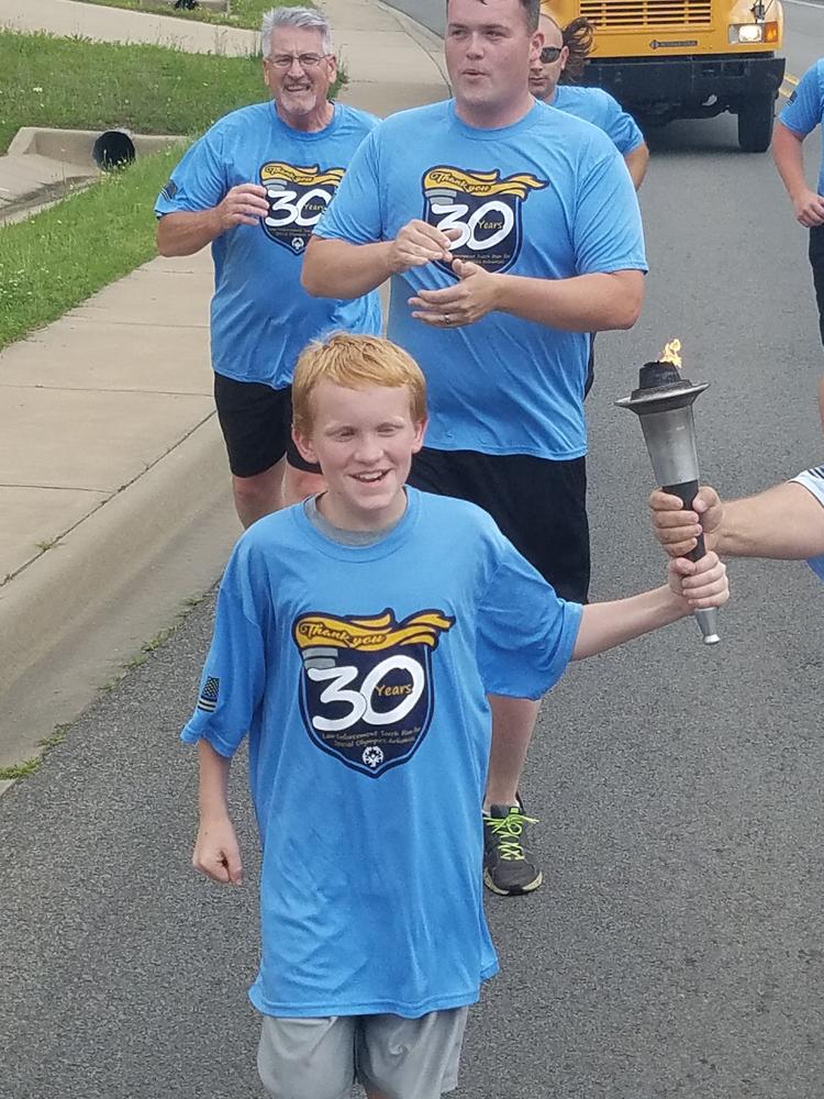 Young boy receiving torch during the Special Olympics Arkansas run.